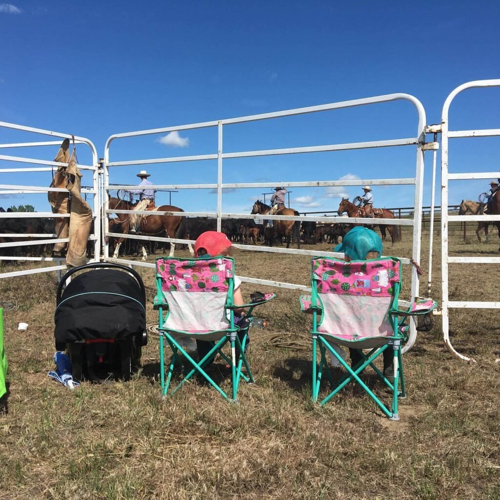 two toddler girls and a baby watching a cattle branding